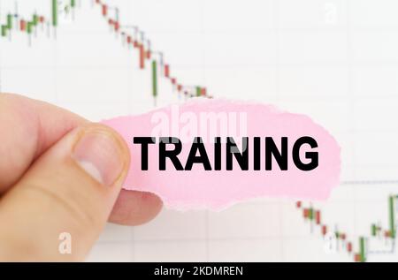 Geschäfts- und Handelskonzept. Vor dem Hintergrund des Zitatdiagramms hält ein Mann ein Schild mit der Aufschrift - TRAINING Stockfoto