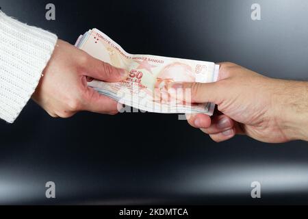 Menschliche Hände tauschen Geld isoliert auf Hintergrund. Türkisches Geld oder türkische Lira. Stockfoto