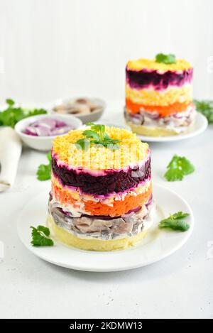 Geschichteter Salat mit Rüben, Hering, Karotten und Kartoffeln auf dem Teller Stockfoto