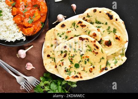 Indisches Naan-Brot und Hühnerfleisch-Chicken-Chicken-Chicken-Chicken auf dunklem Draufsicht, flach liegend Stockfoto