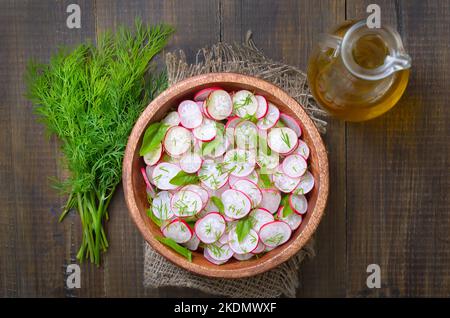 Rettichsalat in Schüssel und frischer Dill auf Holztisch. Draufsicht, flach liegend Stockfoto