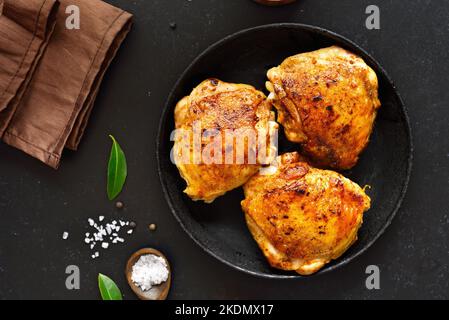 Gebratene Hähnchenschenkel auf dunklem Steingrund. Draufsicht, flach liegend Stockfoto