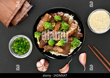 Braten Sie Rindfleisch unter Rühr mit Brokkoli auf schwarzem Stein. Draufsicht, flach liegend Stockfoto