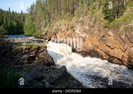 Oulanka National Park. Kiutaköngäs Stromschnellen Wasserfall mit rotem Kalkstein Felswand während eines sommerlichen Sonnenaufgangs in der finnischen Natur, Nordeuropa. Stockfoto