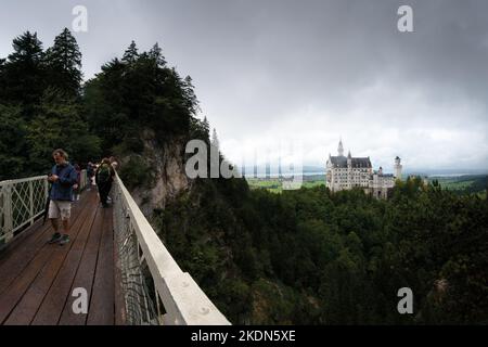 Füssen, Deutschland - 19. August 2022: Schloss Neuschwanstein in Füssen, berühmtes Wahrzeichen Bayerns. Blick auf einen bewölkten Tag mit Menschen und Touristen Stockfoto