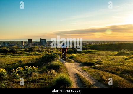 Mountainbiker, die bei Sonnenuntergang im Military Reserve-Gebiet in den Boise Foothills Luft fangen. Stockfoto