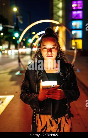 Junge Frau in farbenfroher Beleuchtung am Sonic Walkway in San Jose Stockfoto