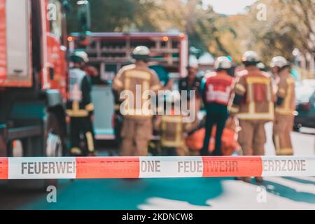 Team von blured Feuerwehrmänner, die durch firetruck auf geschützten Unfallstelle. Fokus auf roten und weißen Sicherheit band. Stockfoto