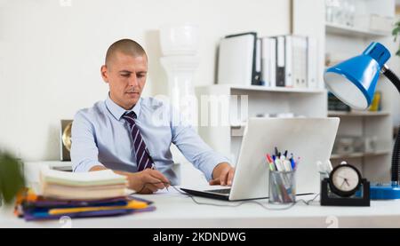 Selbstbewusster erwachsener Mann, der im Büro arbeitet Stockfoto