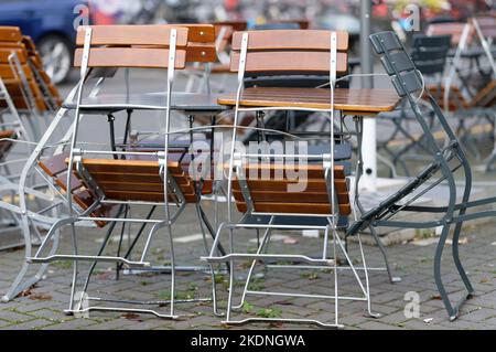 Tische und Stühle der Außengastronomie eines Restaurants auf dem Bürgersteig sind mit Drahtseilen gesichert Stockfoto