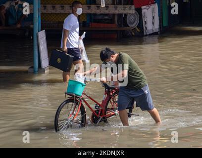 SAMUT PRAKAN, THAILAND, Okt 29 2022, Schiebt Ein Mann sein Fahrrad durch eine überflutete Straße Stockfoto