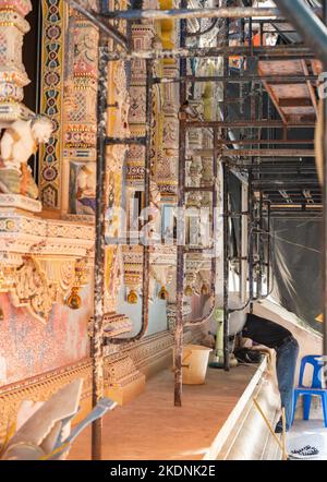 Ein Mann arbeitet, um die Wand eines buddhistischen Tempels, Wat Pariwat Bangkok, Thailand, zu schmücken Stockfoto