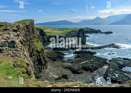 Der Meeresstapel von Dùn Beag auf der Isle of Sanday, Schottland, Großbritannien, mit den Hügeln von Rum dahinter. Stockfoto