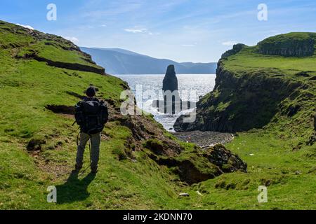 Der Meeresstapel von Dùn Beag auf der Isle of Sanday, Schottland, Großbritannien, mit den Hügeln von Rum dahinter. Stockfoto