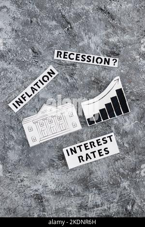 Texte zu Zinssätzen, Inflation und Rezession mit Banksymbol neben dem Diagramm mit nach oben kommenden Statistiken und wirtschaftlichen Kämpfen nach der Pandemie Stockfoto