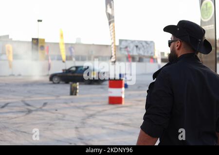 Misrata, Libyen. 07.. November 2022. Ein Polizist steht alarmiert vor dem Autodrift in Misrata. Junge Libyer, die gerne Autos fahren, lieben es zu treiben, aber sie übten es ohne Kontrollen und ohne ein geeignetes Feld dafür. Der Libysche Internationale Automechanic Carnival bietet ihnen jedoch die Möglichkeit, die berühmten Menschen zu treffen, die in diesem Sport treiben, und mit ihnen Unterricht und Erfahrungen zu erhalten. Kredit: SOPA Images Limited/Alamy Live Nachrichten Stockfoto