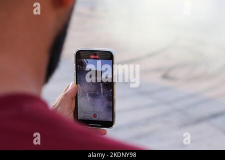 Misrata, Libyen. 07.. November 2022. Ein Zuschauer zeichnet das Autodrift-Ereignis mit seinem Handy auf. Junge Libyer, die gerne Autos fahren, lieben es zu treiben, aber sie übten es ohne Kontrollen und ohne ein geeignetes Feld dafür. Der Libysche Internationale Automechanic Carnival bietet ihnen jedoch die Möglichkeit, die berühmten Menschen zu treffen, die in diesem Sport treiben, und mit ihnen Unterricht und Erfahrungen zu erhalten. Kredit: SOPA Images Limited/Alamy Live Nachrichten Stockfoto