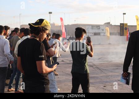 Misrata, Libyen. 07.. November 2022. Eine Gruppe von Zuschauern beobachtet und zeichnet das Autodriftereignis auf. Junge Libyer, die gerne Autos fahren, lieben es zu treiben, aber sie übten es ohne Kontrollen und ohne ein geeignetes Feld dafür. Der Libysche Internationale Automechanic Carnival bietet ihnen jedoch die Möglichkeit, die berühmten Menschen zu treffen, die in diesem Sport treiben, und mit ihnen Unterricht und Erfahrungen zu erhalten. (Foto von Islam Alatrash/SOPA Images/Sipa USA) Quelle: SIPA USA/Alamy Live News Stockfoto