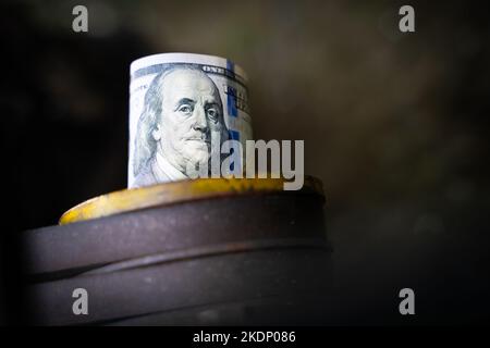 100-Dollar-Schein in Nahaufnahme einer Traktorrolle mit verschwommenem Hintergrund. Ein zusammengerollter Dollarschein wird in ein Detail aus einer landwirtschaftlich geprägten Ader eingefügt Stockfoto