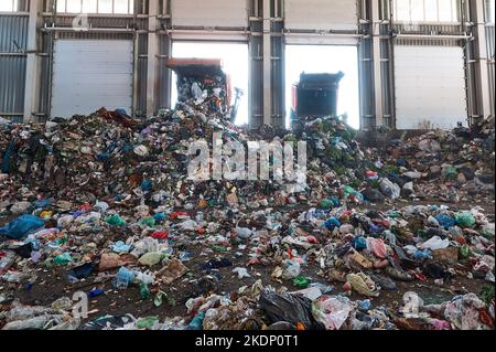 Der Müllwagen entlädt den Hausmüll in der Eingangskammer einer Abfallsortieranlage Stockfoto