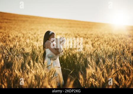 Es entlädt sich zu einem perfekten Tag. Ein süßes kleines Mädchen, das mit ihrem Teddybären in einem Kornfeld spielt. Stockfoto