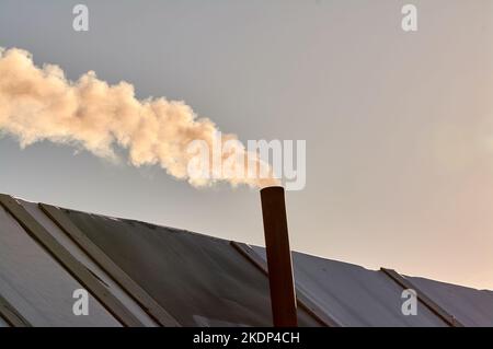 Rauch kommt aus dem Schornstein der Bourgeoisie, der Ofen wird erhitzt. Stockfoto