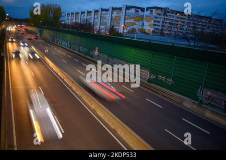 PRODUKTION - 07. November 2022, Sachsen-Anhalt, Magdeburg: Der abendliche Berufsverkehr rollt an Wohngebäuden der Landeshauptstadt Magdeburg auf der Stadtautobahn vorbei. Aufgrund der langen Belichtung hinterlassen die Lichter der Fahrzeuge Streifen auf dem Bild. In Sachsen-Anhalt fahren die meisten Menschen nach Magdeburg. Dies wird durch neue Zahlen des Staatlichen Statistikamtes bestätigt. Demnach hatte die Landeshauptstadt 2021 mit knapp 18.000 arbeitenden Menschen die höchste Pendlerbilanz in Sachsen-Anhalt. Das bedeutet, dass mit rund 53.000 deutlich mehr Erwerbstätige pendeln Stockfoto