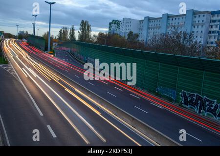 PRODUKTION - 07. November 2022, Sachsen-Anhalt, Magdeburg: Der abendliche Rushhour-Verkehr rollt über die Stadtautobahn der Landeshauptstadt Magdeburg. Aufgrund der langen Belichtung hinterlassen die Lichter der Fahrzeuge Streifen auf dem Bild. In Sachsen-Anhalt fahren die meisten Menschen nach Magdeburg. Dies wird durch neue Zahlen des Staatlichen Statistikamtes bestätigt. Demnach hatte die Landeshauptstadt 2021 mit knapp 18.000 arbeitenden Menschen die höchste Pendlerbilanz in Sachsen-Anhalt. Das bedeutet, dass mit rund 53.000 deutlich mehr Erwerbstätige in der Stadt zur Arbeit pendelten als p Stockfoto