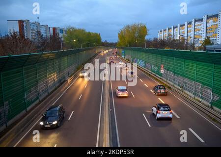 PRODUKTION - 07. November 2022, Sachsen-Anhalt, Magdeburg: Der abendliche Berufsverkehr rollt an Wohngebäuden der Landeshauptstadt Magdeburg auf der Stadtautobahn vorbei. Aufgrund der langen Belichtung hinterlassen die Lichter der Fahrzeuge Streifen auf dem Bild. In Sachsen-Anhalt fahren die meisten Menschen nach Magdeburg. Dies wird durch neue Zahlen des Staatlichen Statistikamtes bestätigt. Demnach hatte die Landeshauptstadt 2021 mit knapp 18.000 arbeitenden Menschen die höchste Pendlerbilanz in Sachsen-Anhalt. Das bedeutet, dass mit rund 53.000 deutlich mehr Erwerbstätige pendeln Stockfoto