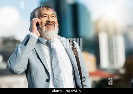 Geschäftsmann, Lächeln und Telefonanruf in der Stadt für Kommunikation, Unterhaltung oder Gespräche im Freien. Glücklicher Mann, der ein erfolgreiches Geschäft hat Stockfoto