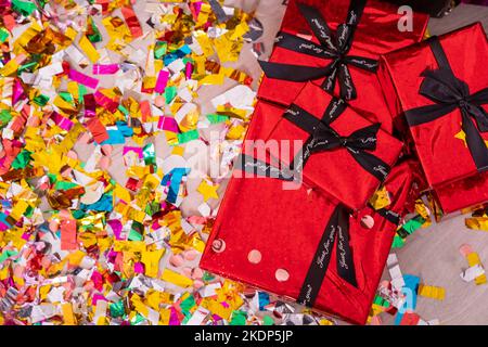 Weihnachtskomposition. Bunte Dekorationen, Geschenke auf Konfetti-Hintergrund. Weihnachten, Winter, Neujahr Konzept. Flach liegend, Draufsicht.Geschenke und Stockfoto