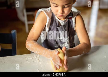 Nahaufnahme der Kinderhände, die den Teig kneten Stockfoto