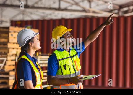 Indische männliche Arbeiter, die mit weiblichen Teams arbeiten, arbeiten in der Cargo-Logistik-Industrie und helfen zusammen glückliches Lächeln Stockfoto