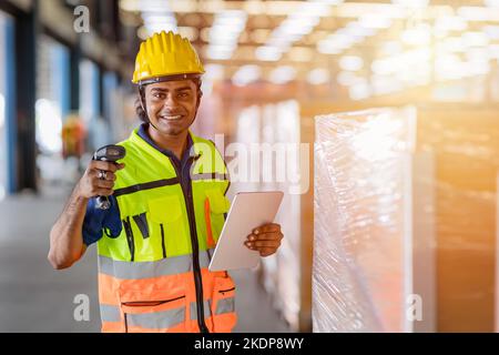 Portrait glücklicher indischer Arbeiter arbeitet im Lagerhaus als Versandpersonal, das den Frachtkasten überprüft Stockfoto