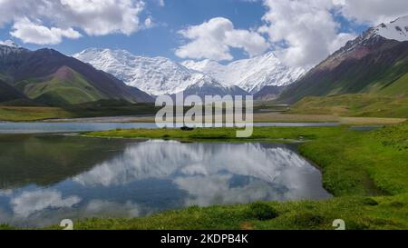 Blick auf das Achik Tash Basislager des Lenin Peak alias Ibn Sina Peak mit Spiegelung im See im Trans Alay oder Trans Alai Gebirge, im Süden Kirgisistans Stockfoto