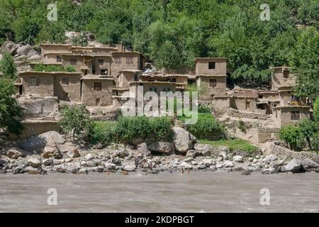 Blick auf das abgelegene, ländliche afghanische Bergdorf am Ufer des Panj-Flusses vom Darvaz-Bezirk in Gorno-Badakshan, Tajikistan Pamir Stockfoto