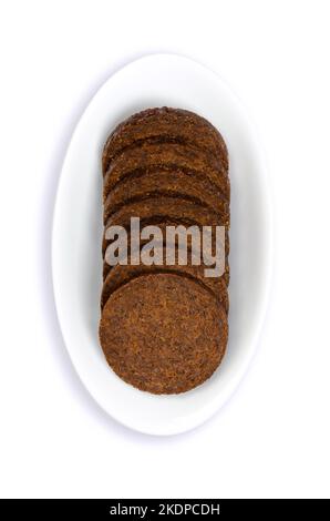 Pumpernickel in Scheiben in einer weißen Schüssel. Kreisförmige Scheiben eines schweren, leicht süßen, dunkelbraunen Roggenbrotes, traditionell mit Sauerteig-Vorspeise hergestellt. Stockfoto