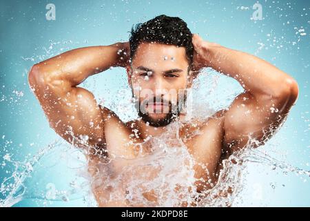 Wasser, Spritzer und der Mann wäscht seinen Körper auf einem blauen Studiohintergrund für Gesundheit und Wellness. Körperpflege, Hygiene und der Mensch reinigt oder reinigt seinen Körper Stockfoto