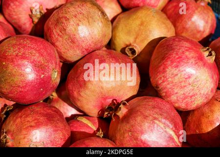 Saftig reife Granatapfelfrüchte auf der Markttheke für Saft. Granatapfelernte auf landwirtschaftlichem Betrieb, Vitamine, Früchte, Tropenkonzept. Hochwertige Fotos Stockfoto