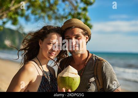 Der Sommer ist genau so, wie wir ihn mögen. Porträt eines glücklichen jungen Paares, das Cocktails genießt und sich am Strand entspannt. Stockfoto