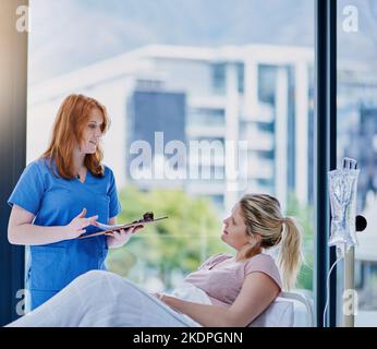 Ich habe einige Post-op-Ratschläge für Sie. Ein junger Arzt gibt ein Patienten-Feedback in einer Krankenhausabteilung. Stockfoto