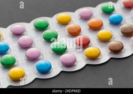 Mehrfarbige Pillen in einer Blisterpackung in Nahaufnahme auf grauem Hintergrund. Stockfoto