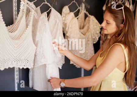 Eine junge Frau, die in einer Boutique durch die Kleidung stöbert. Stockfoto