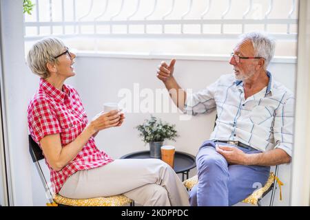 Seniorenpaar sitzt und redet auf der Terrasse bei sich zu Hause. Freizeit. Stockfoto