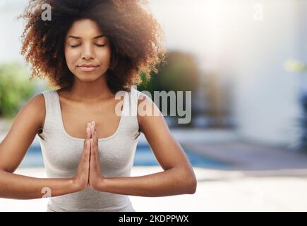 Balance zwischen Körper und Geist. Eine sportliche junge Frau, die im Freien Yoga praktiziert. Stockfoto