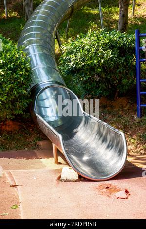 Zylinderrutsche aus Edelstahl auf dem Spielplatz im Park Stockfoto