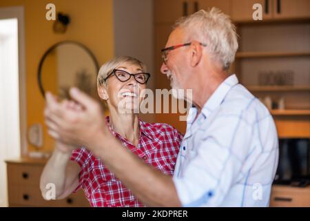 Glückliches Seniorenpaar tanzt zu Hause. Senioren, die eine schöne Zeit zusammen haben. Stockfoto