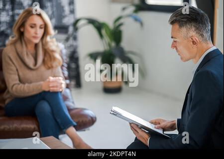 Blonde Frau, die mit dem Psychiatrie spricht und gestresst aussieht Stockfoto