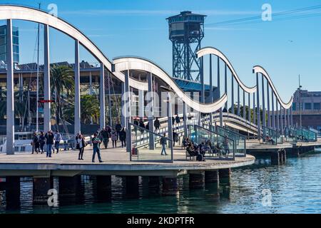 Barcelona, Spanien - 15. 2013. Dezember: Menschen, die die Rambla de Mar überqueren, wandern in Port Vell. Im Hintergrund befindet sich der Torre Sant Sebastià. Stockfoto