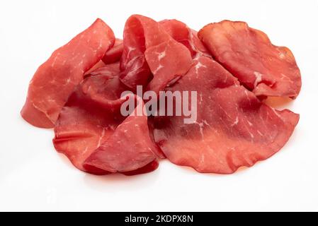 Auf weiße, italienische getrocknete Rindersalami aus dem Valtellina isolierte Scheiben von Bressaola Stockfoto
